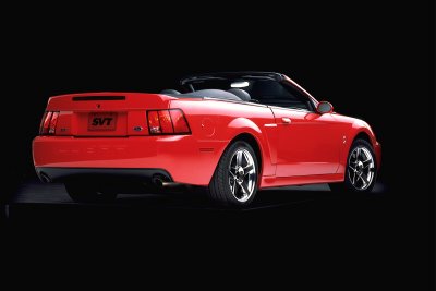 2003 Ford Mustang - This red 2003 Ford SVT Mustang convertible is shown from the rear three-quarter angle against a black background.