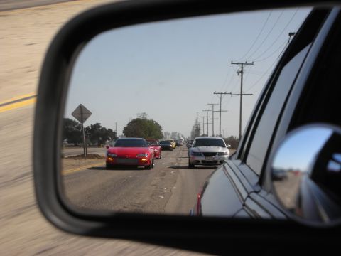 1992 Ford Crown Victoria - A convoy of sports cars travels down a highway, seen from the perspective of a side mirror.