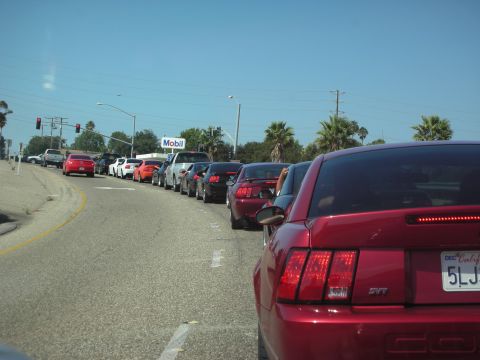 1992 Ford Crown Victoria - A line of cars, including several Ford Mustangs, are stopped in traffic near a Mobil gas station.