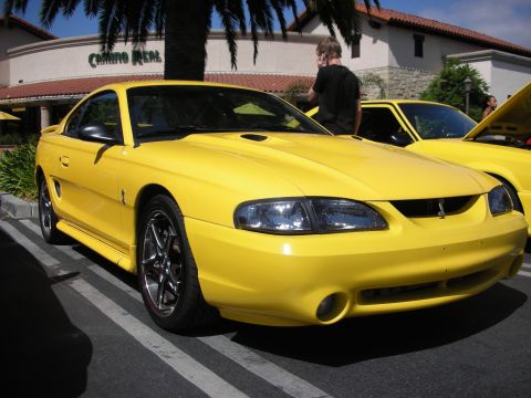 1992 Ford Crown Victoria - A yellow Ford Mustang is parked in a lot next to another yellow vehicle.