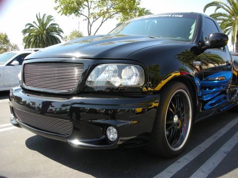 1992 Ford Crown Victoria - A black Ford F-150 Lightning pickup truck is parked in a lot, reflecting another vehicle.