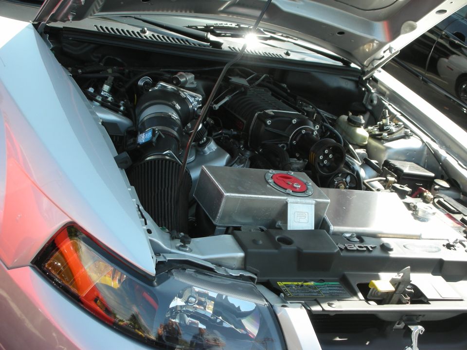 Engine bay with a supercharger, intake, and custom coolant tank
