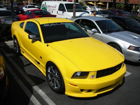 1992 Ford Crown Victoria - A bright yellow Ford Mustang is parked in a lot, with other vehicles visible around it.