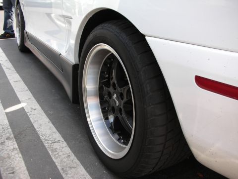 1992 Ford Crown Victoria - Side view of a car's wheel and lower body trim, with aftermarket wheels installed.