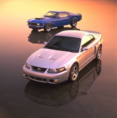 2003 Ford Mustang - A silver 2003 Ford Mustang is shown alongside a blue 1969 Ford Mustang, highlighting the evolution of the iconic muscle car.