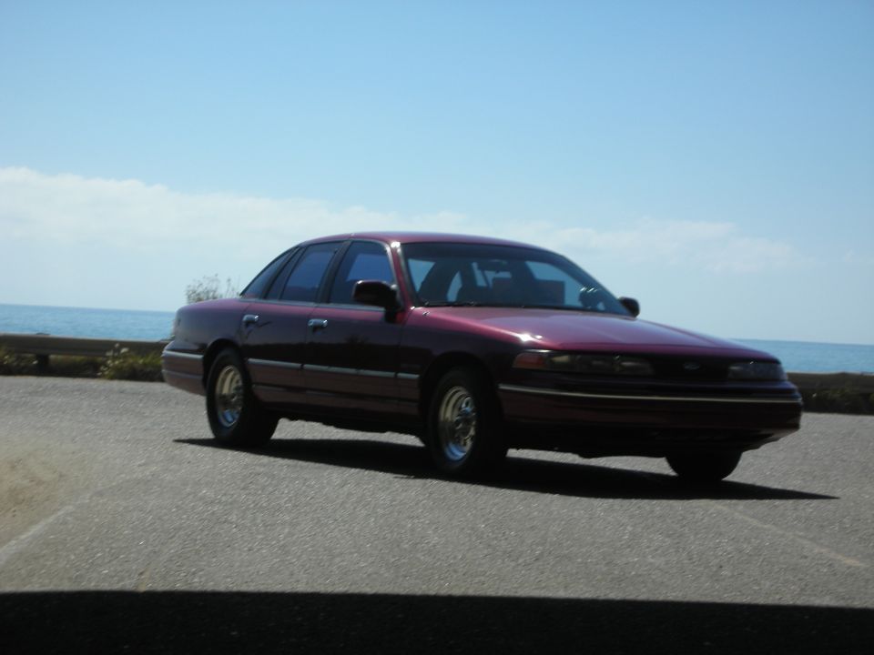 1992 Ford Crown Victoria sedan parked on asphalt with ocean and sky in background