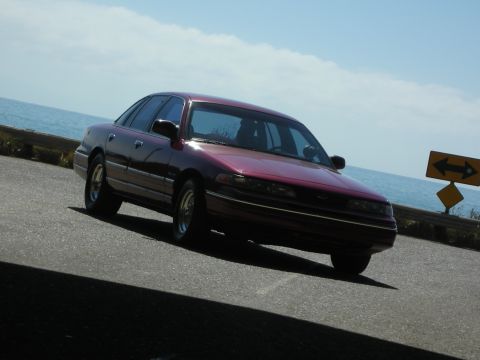 1992 Ford Crown Victoria - A maroon 1992 Ford Crown Victoria is seen driving on a road next to the ocean.
