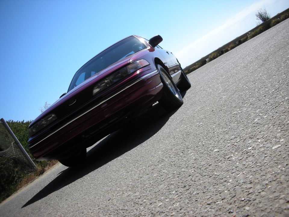 maroon sedan parked on asphalt, low angle shot
