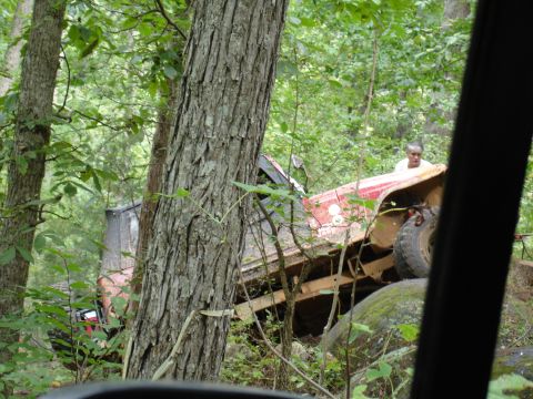 1996 Ford Bronco - Off-road vehicle stuck on rocks in a forest, with a person observing.