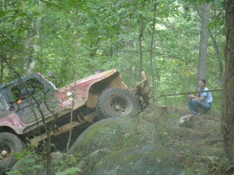 1996 Ford Bronco - A red Jeep Wrangler navigates a challenging rocky terrain on an off-road trail.
