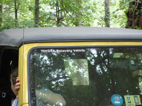 1996 Ford Bronco - A yellow jeep with a black soft top is parked outdoors, with a sticker on the rear window indicating it is a recovery vehicle.