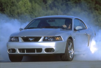 2003 Ford Mustang - Silver 2003 Ford Mustang performing a burnout with smoke surrounding the vehicle.