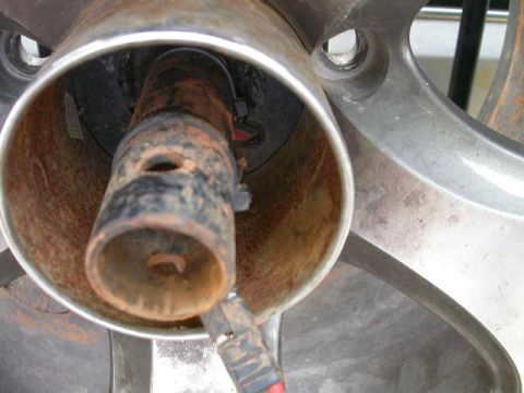 1990 Ford Bronco - A close-up view of a rusty metal component, possibly from a vehicle's undercarriage, with a wire connector visible.