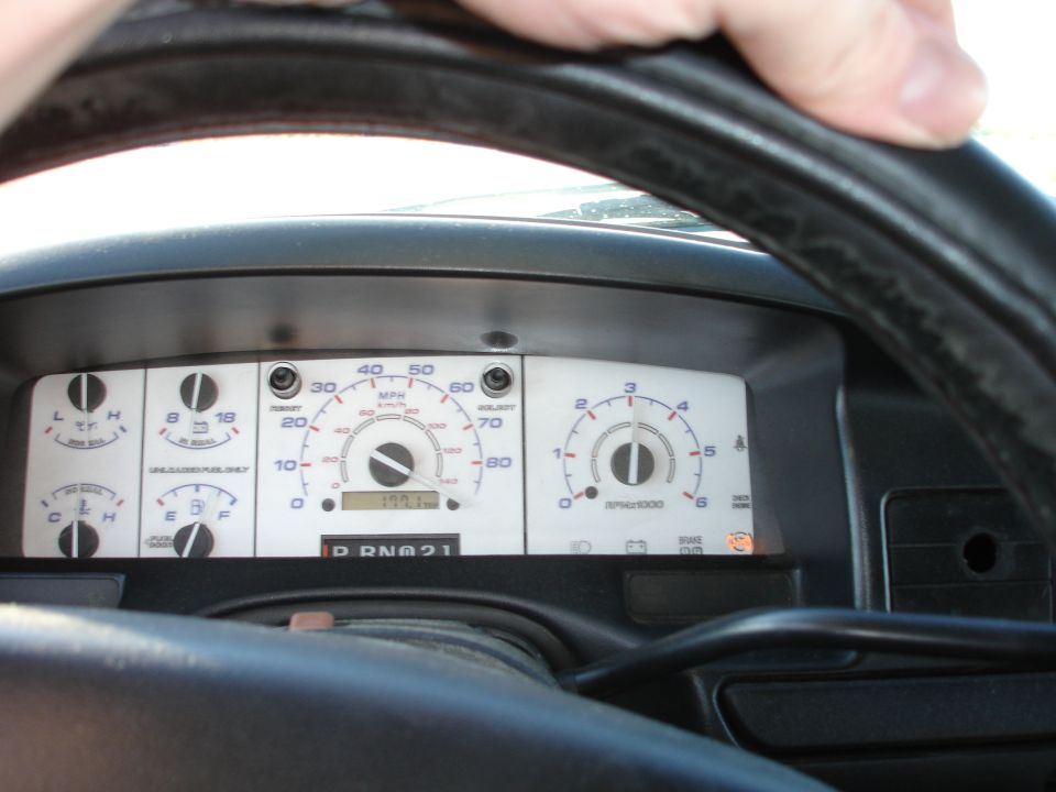 White-face Ford truck instrument cluster seen through the black steering wheel