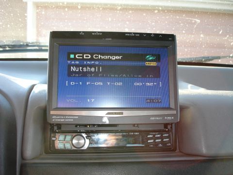 1996 Ford Bronco - Close-up of a car's audio system, a screen displaying song information and volume level.