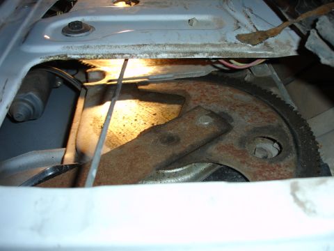 1996 Ford Bronco - The interior of a vehicle door reveals a rusty window regulator mechanism with a motor and gear.