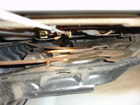 1996 Ford Bronco - Underside view of a vehicle's seat adjustment mechanism, showing cables and linkages.