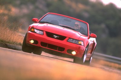 2003 Ford Mustang - Red 2003 Ford Mustang convertible captured in motion on a winding road.
