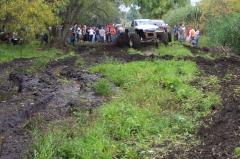 1978 Ford Bronco - Modified trucks navigate a challenging muddy course with onlookers present.