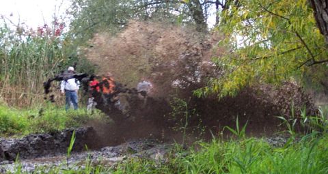 1978 Ford Bronco - A vehicle navigates a muddy off-road course, kicking up a large spray of mud.