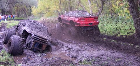 1978 Ford Bronco - Two vehicles are stuck in deep mud during an off-road event.