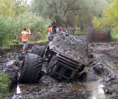 1978 Ford Bronco - A muddy off-road event shows vehicles struggling through deep mud pits with onlookers observing.
