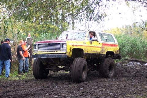 1978 Ford Bronco - This heavily modified SUV is deep in the mud, with onlookers observing the scene.