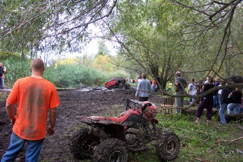 1978 Ford Bronco - An ATV is stuck in the mud at an outdoor event with spectators gathered around.