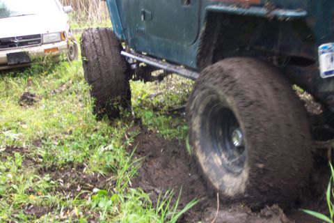 1978 Ford Bronco - A green off-road vehicle is stuck in the mud, with another vehicle visible behind it.