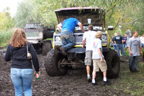 1978 Ford Bronco - Off-road vehicles stuck in mud with people attending to one of them.