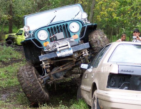 1978 Ford Bronco - A teal Jeep Wrangler is stuck on the side of a tan Dodge during an off-road event.