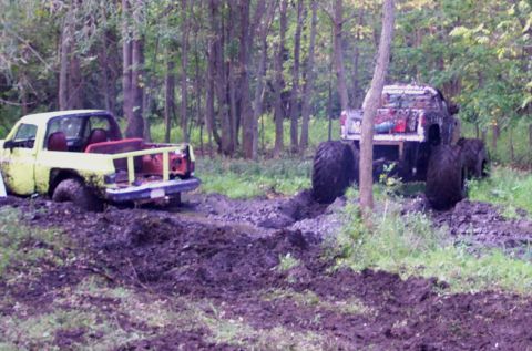 1978 Ford Bronco - Two trucks are stuck in the mud during an off-road event in a forest.