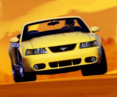 2003 Ford Mustang - A yellow 2003 Ford Mustang convertible is shown from the front, driving against an orange background.