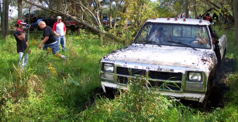 1978 Ford Bronco - White Dodge pickup truck stuck in mud, with other vehicles and people in the background.