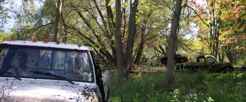 1978 Ford Bronco - Several vehicles are parked in a wooded area with trees showing fall colors.
