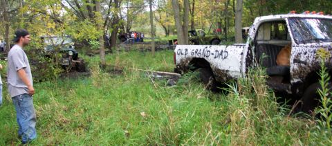 1978 Ford Bronco - Several trucks are stuck in the mud in a wooded area, with people observing the scene.