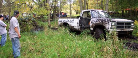 1978 Ford Bronco - A white pickup truck is stuck in the mud, with people watching in the background.