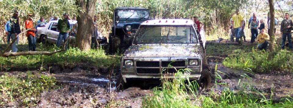 Muddy pickup truck stuck in mud, front view. Another Jeep is behind it