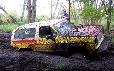 1978 Ford Bronco - This heavily mud-caked SUV, possibly a 1978 model, is deeply stuck in a muddy off-road environment.