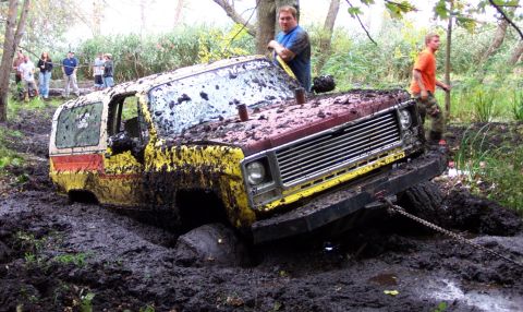 1978 Ford Bronco - Off-road vehicle deep in mud during a bogging event, with onlookers.