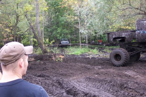 1978 Ford Bronco - Off-road vehicles navigate a muddy course in a wooded area, with spectators watching.