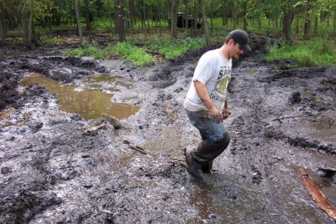 1978 Ford Bronco - A man navigates a treacherous muddy path in a wooded area, with an ATV partially visible in the background.