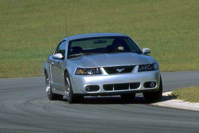 2003 Ford Mustang - Silver 2003 Ford Mustang coupe on a road with green grass in the background.