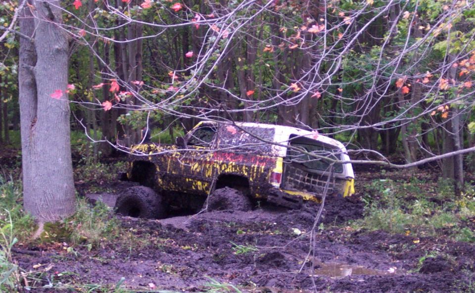 Mud-covered 1978 Ford Bronco stuck in a muddy wooded area