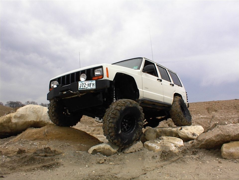 White Jeep Cherokee XJ climbing rocks, front 3/4 view