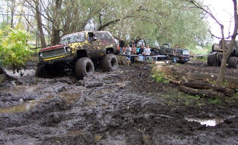 1978 Ford Bronco - Several off-road vehicles are stuck in thick mud during an event.