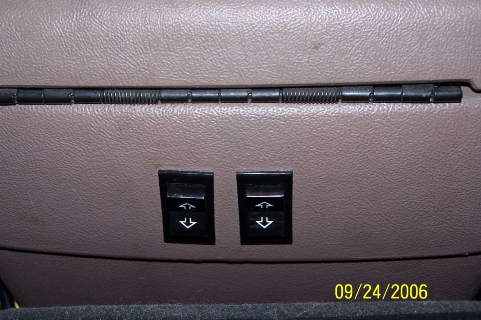 Two power window switches with arrow symbols on a brown interior panel of a 1994 Ford Bronco