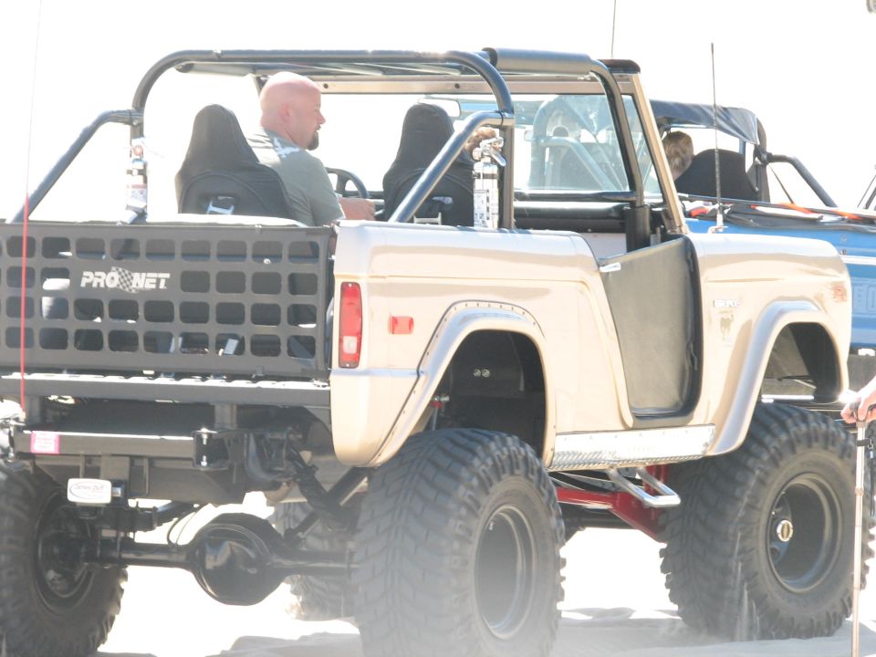 Tan early Bronco with roll cage and tube rear, rear three-quarter view