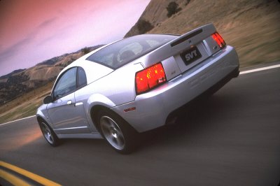 2003 Ford Mustang - Rear view of a silver 2003 Ford Mustang SVT driving on a road.
