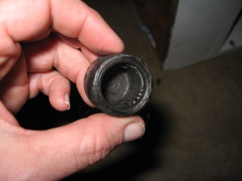 1978 Ford Bronco - A hand holds a small grease-caked cup-shaped bearing or bushing cap pulled off a vehicle, its interior packed with dark grease and stray fi…